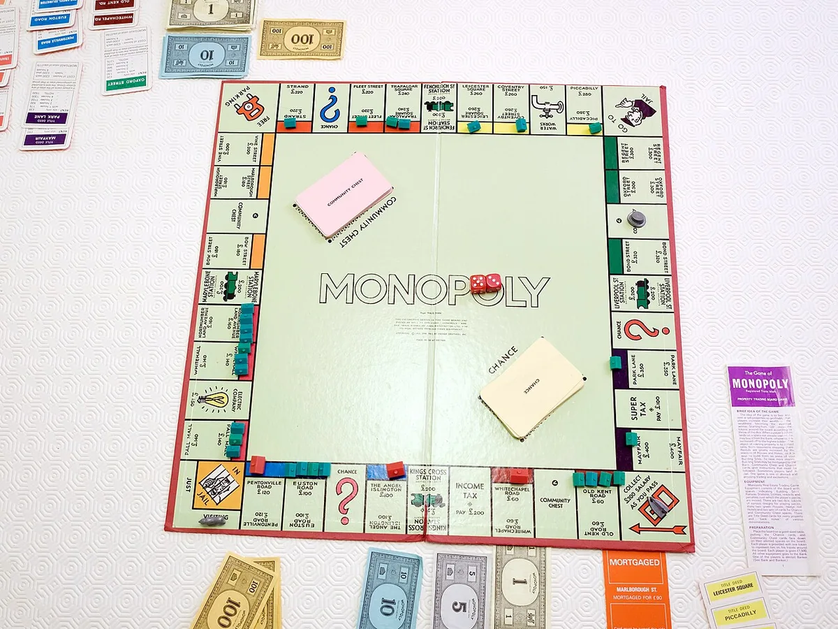 A classic British Monopoly board in mid-game with tokens, houses, dice, cards and paper money.