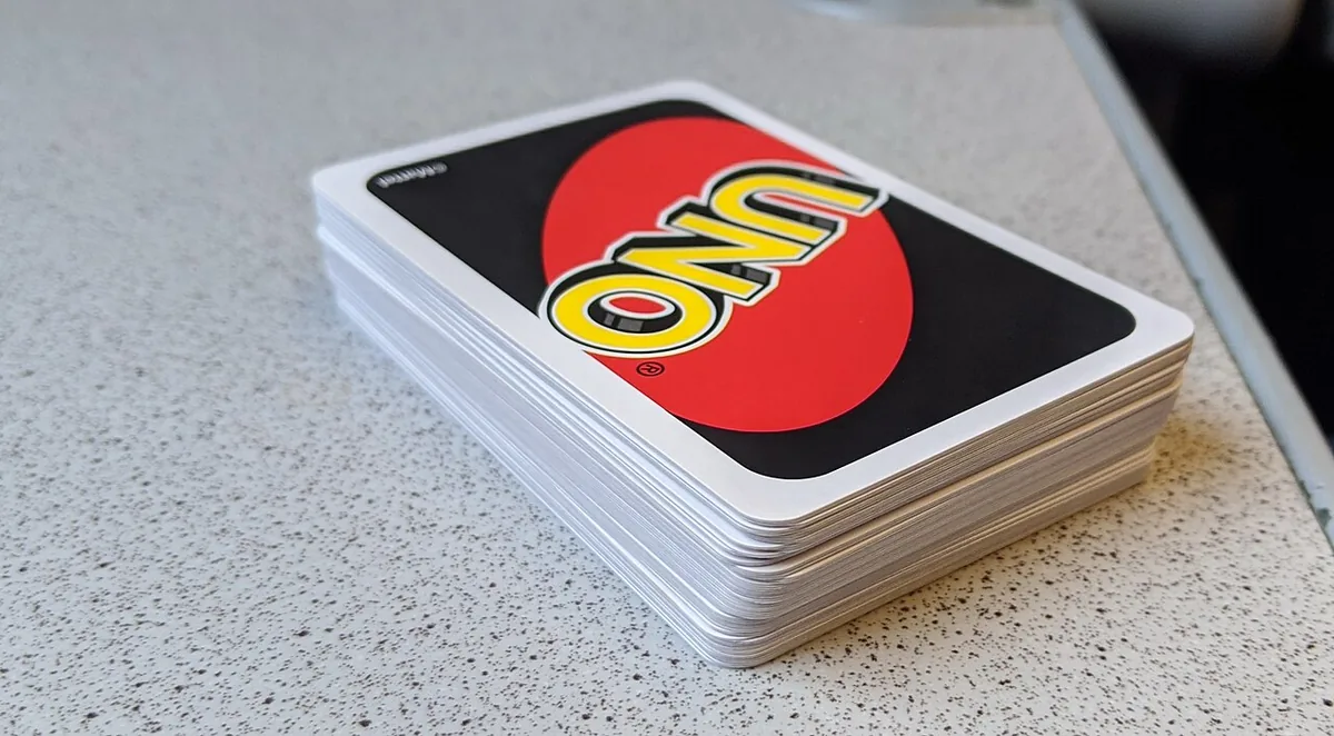 A stack of standard UNO cards lying face down, showing the red and black UNO card back